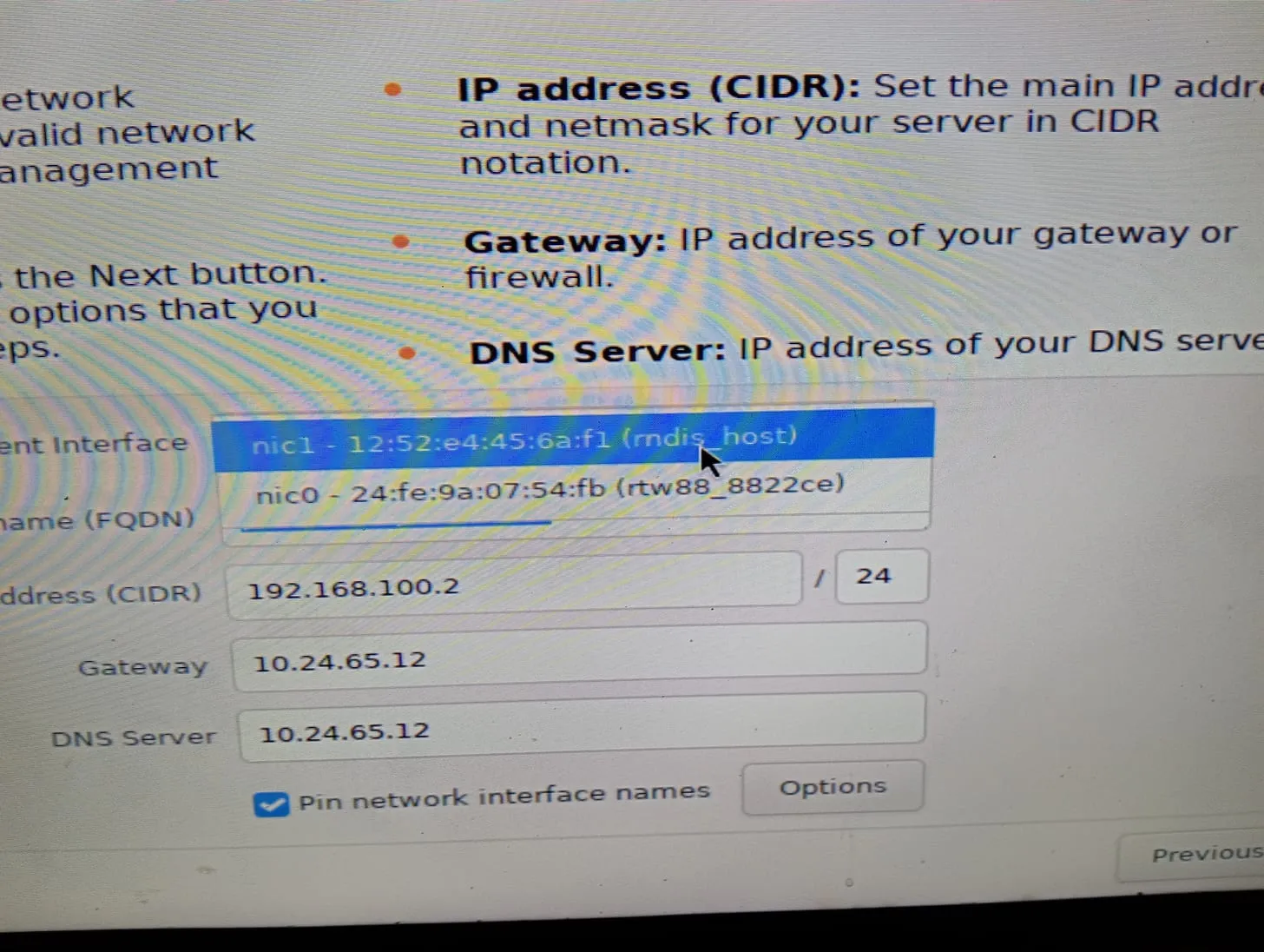 Tela de rede do instalador com a lista de interfaces aberta: nic1 (rndis_host, o celular) selecionada e nic0 (rtw88_8822ce, a placa Wi-Fi)
